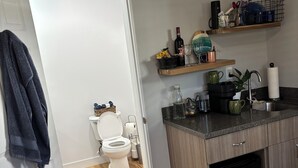 Een moderne keuken met houten kastjes, een zwarte vaatwasser en een aanrecht met diverse spullen.