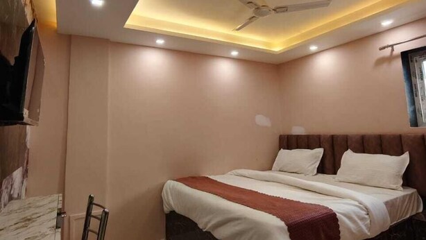 A bedroom with a bed, a ceiling fan, recessed lighting, and a marble floor. - Trinetra Homestay (Varanasi)