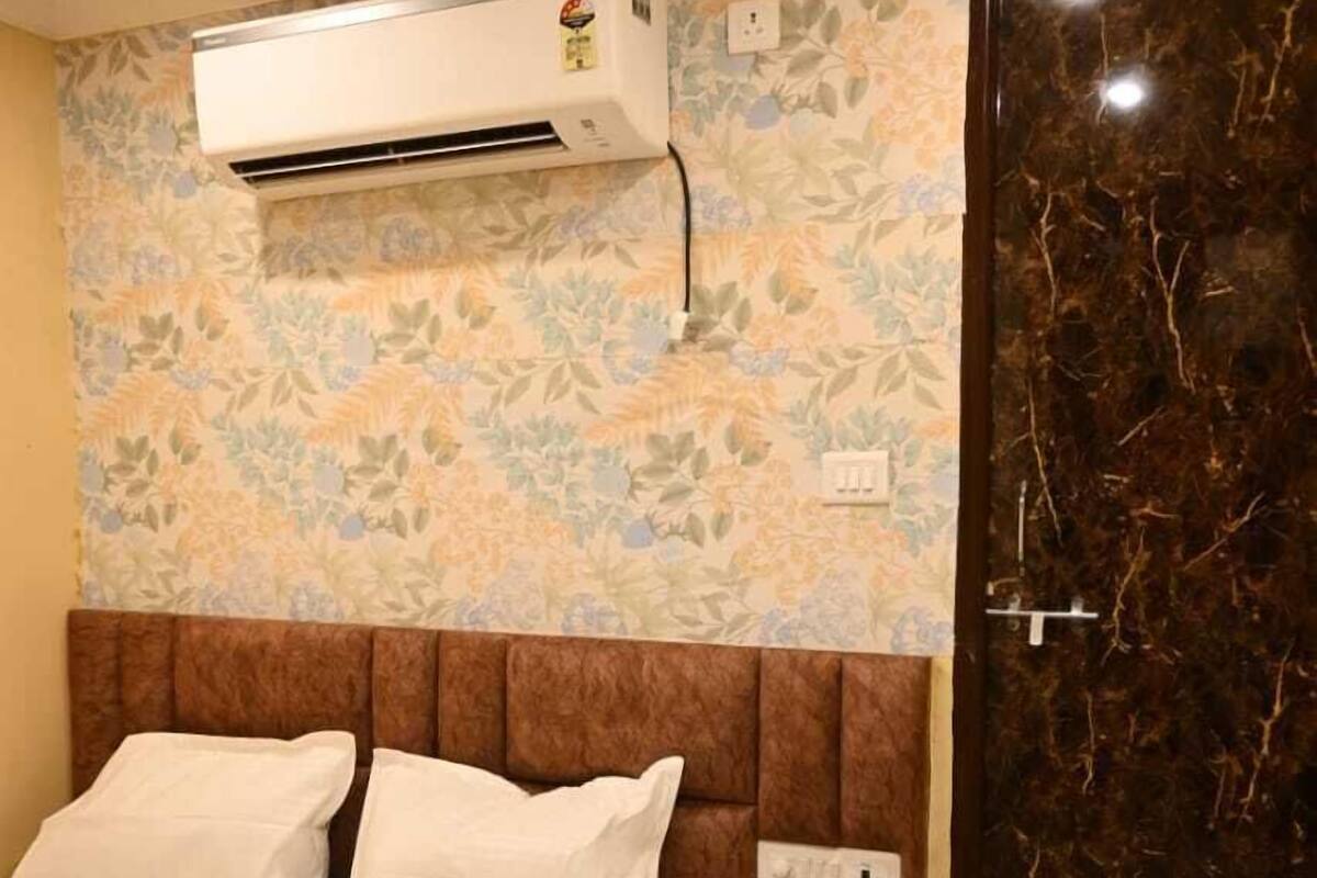 Ett hotellrum med en säng, en luftkonditioneringsanläggning, en telefon och en dörr med marmorliknande mönster.