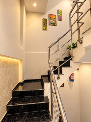 A staircase with black marble steps, metal handrails, and a wall-mounted fire extinguisher. - Trinetra Homestay (Varanasi)