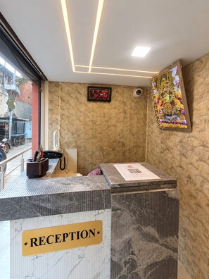 A reception area with a marble counter, a clock, and a framed artwork on the wall. - Trinetra Homestay (Varanasi)