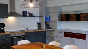 Eine moderne Küche mit einem Holztisch, weißen Stühlen und einem eingebauten Backofen.