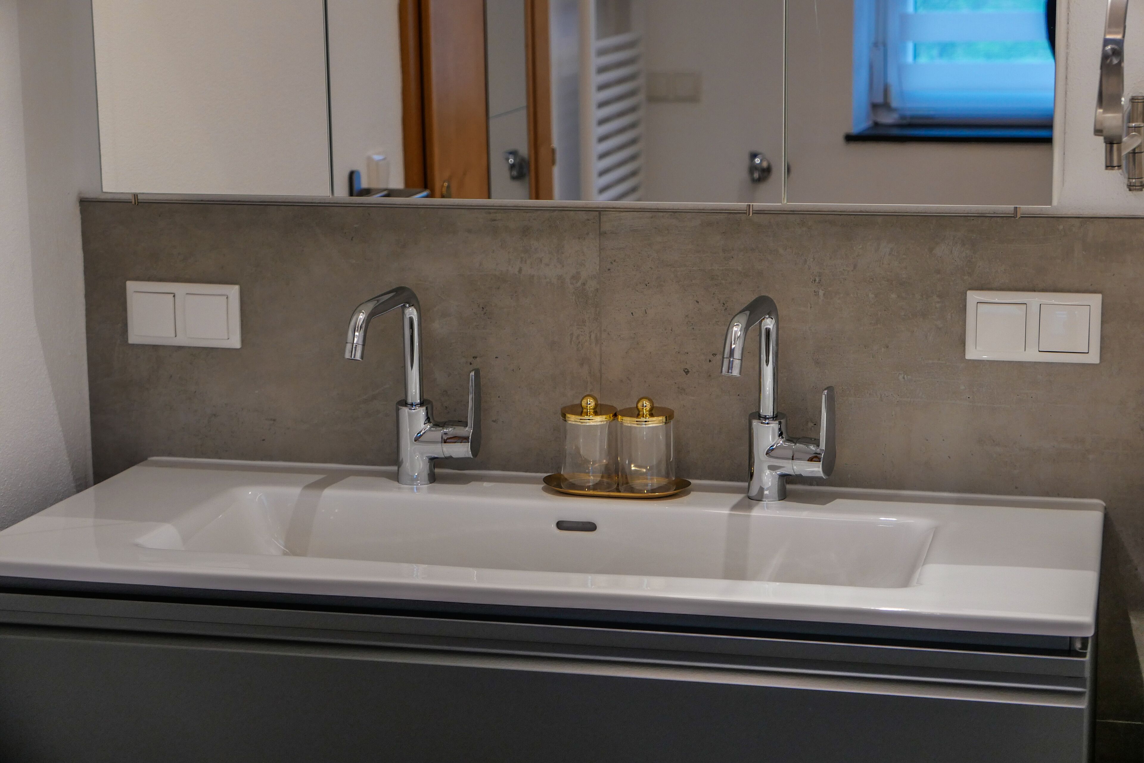 A bathroom with a white sink, two faucets, and a mirror above.