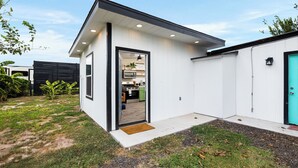 Een modern huis met een witte gevel, een zichtbare keuken en een groene deur.