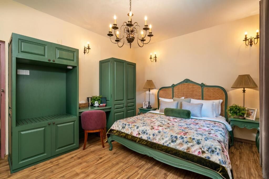 Un dormitorio con una cama grande, un armario verde y una araña.