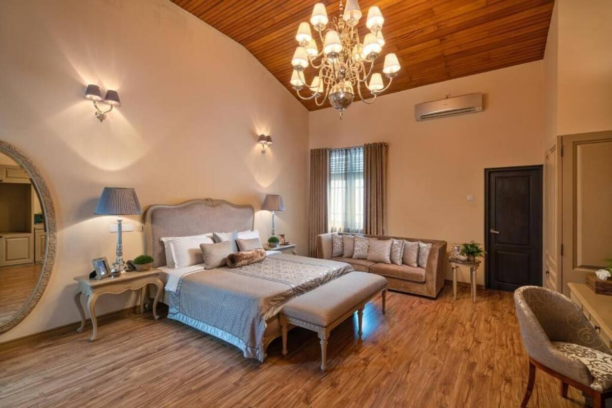 Un dormitorio espacioso con una cama grande, un sofá, una silla y una araña.