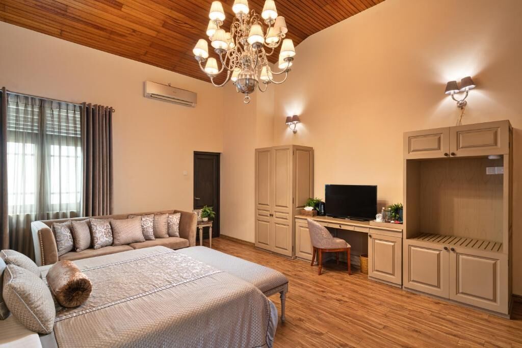 A spacious bedroom with a large bed, a desk with a TV, and built-in wardrobes.