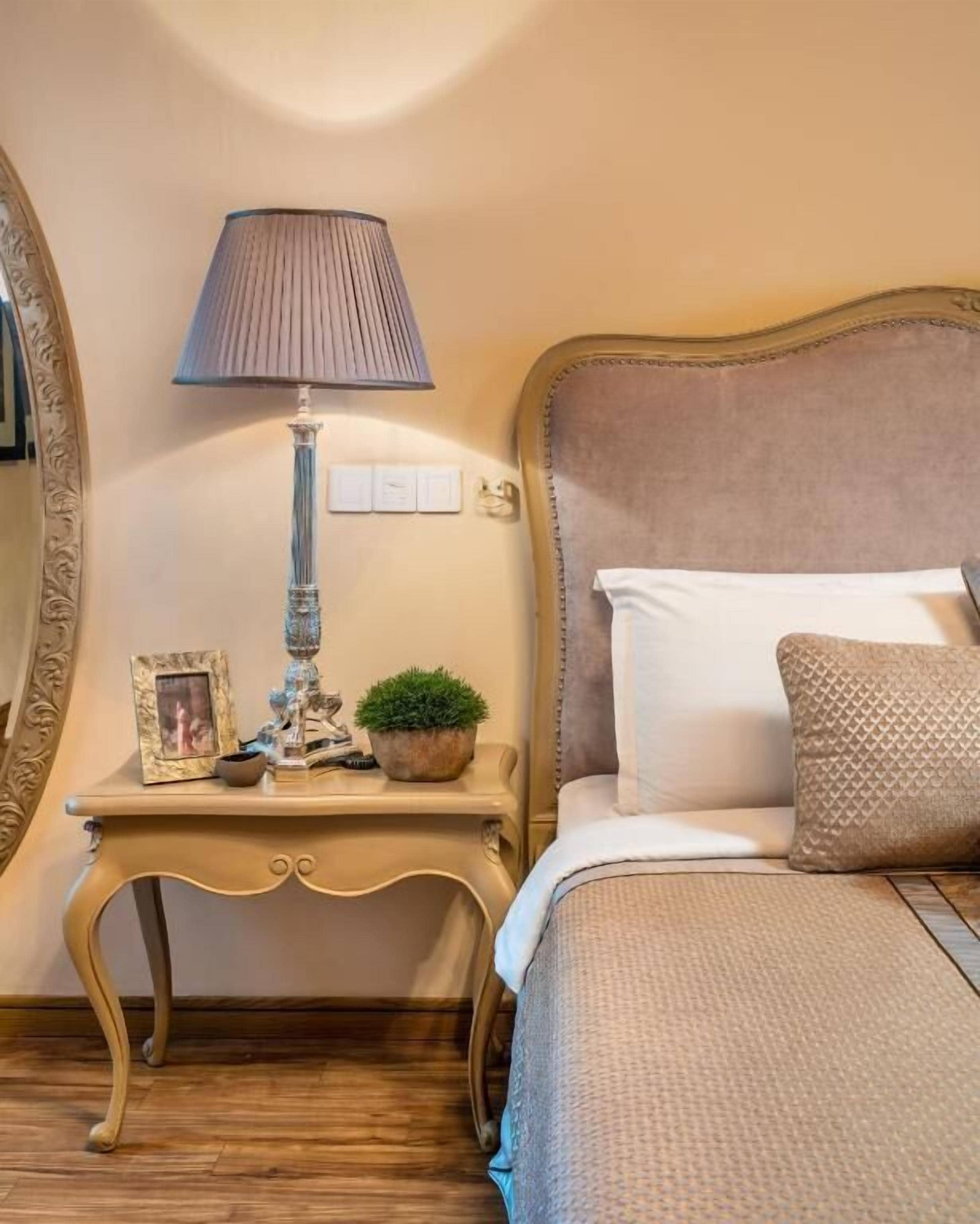 Une chambre à coucher bien rangée, avec un lit, une table de chevet, une lampe et des objets décoratifs.