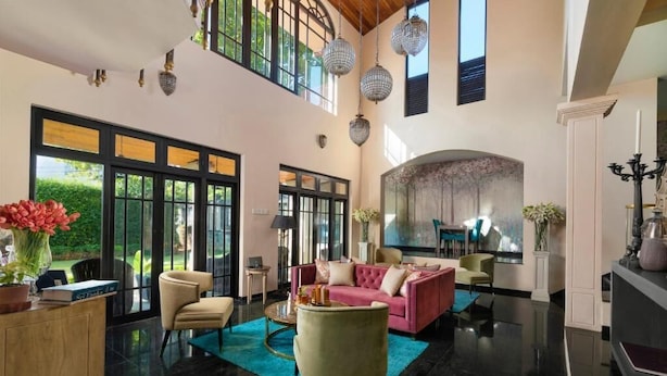 A spacious living area with a large sofa, a coffee table, and a fireplace. There are large windows and a chandelier. - Clove Villa Kandy (Kandy)