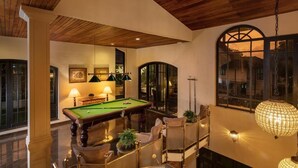 A billiards room with a pool table, comfortable seating, and a large arched window. - Clove Villa Kandy (Kandy)