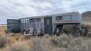 A stationary trailer with a kitchen area, two wooden chairs, and a grill. - Dark Sky · Stargazer Horse Trailer · Edge of the Alvord Desert (Princeton)