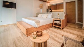A modern bedroom with a large bed, wooden headboard, bedside tables, a TV mounted on the wall, and a ceiling fan. - Mangrove View with Rooftop Pool + Beach Access (Puerto Morelos)