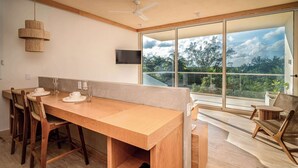 A modern dining area with a wooden table, chairs, and a television mounted on the wall. - Modern & Peaceful GRETA Apartment | Fast WiFi (Puerto Morelos)