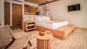 A modern bedroom with a bed, wooden furniture, a TV, and a small table with a bowl and glass. - Rooftop Pool, Fast WiFi & Nature Views at Greta (Puerto Morelos)