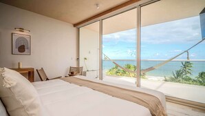 A bedroom with a large bed, a view of the ocean, and a hammock outside. - Modern Seafront Unit | Infinity Pool, Gym (Puerto Morelos)