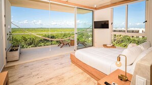 A bedroom with a large bed, a TV, and a balcony with a hammock. - Modern & Peaceful Getaway | Eco-Luxury in Greta (Puerto Morelos)