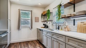 A modern kitchen with a dishwasher, sink, and wooden countertop. - Houston Hideaway Steps from Rice Village Fun (Houston)