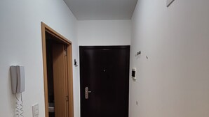 En hall med en trädörr, en dörrmatta, en telefon och en lampa.