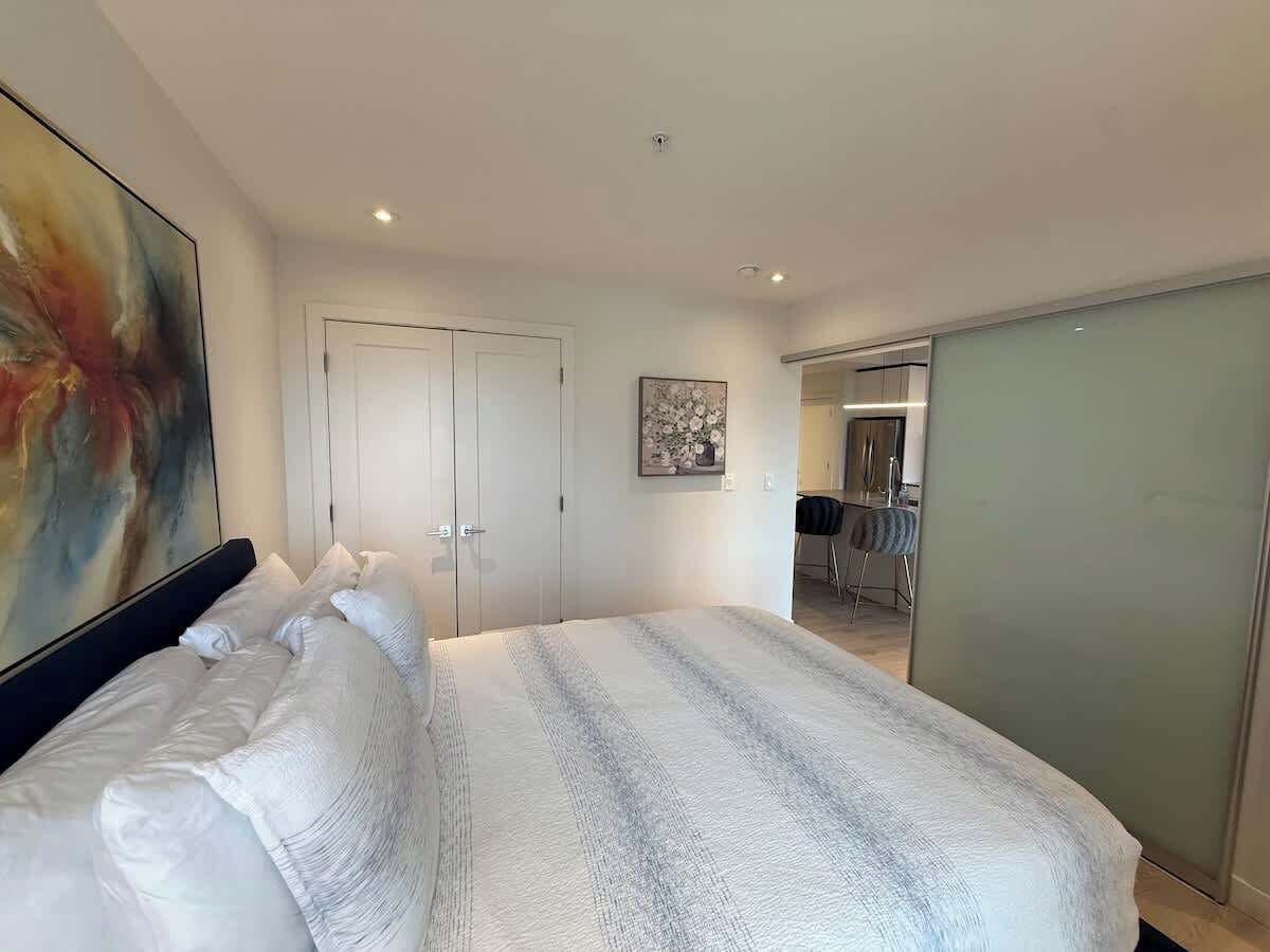 Une chambre d’hôtel moderne avec un grand lit, une armoire et un tableau au mur.