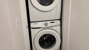 Un cuarto de lavandería con dos lavadoras Samsung de carga frontal apiladas verticalmente.
