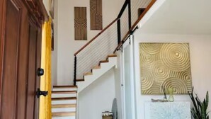 A modern interior with a wooden staircase, a bench, and a decorative wall piece. - Casita Lotus cozy little loft on an Orchard (El Paso)