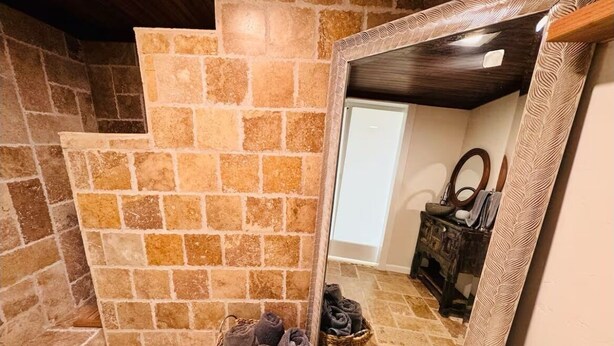 A stone-walled bathroom with a mirror, a wooden bench, and two baskets of towels. - Casita Lotus cozy little loft on an Orchard (El Paso)