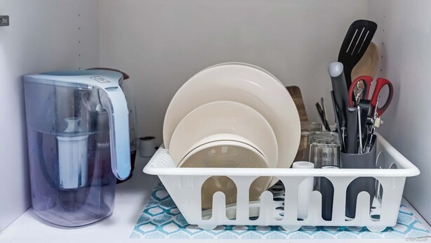 Een kitchenette met een waterdispenser, een afwasschaal met borden en bestek.