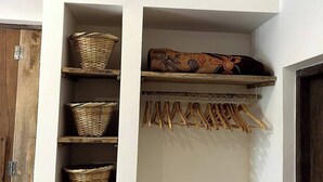 Paredes brancas com prateleiras exibindo cestos e cabides de madeira.