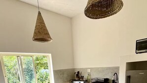 Cozinha com ilha central, geladeira e janela com vista para vegetação.