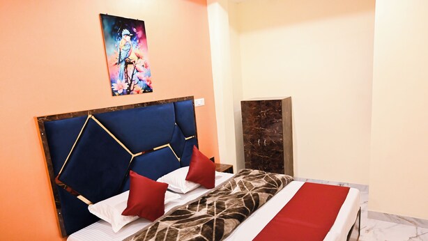 A hotel room with a bed, a headboard, a painting, and a marble floor. - Amaya Deluxe (Varanasi)