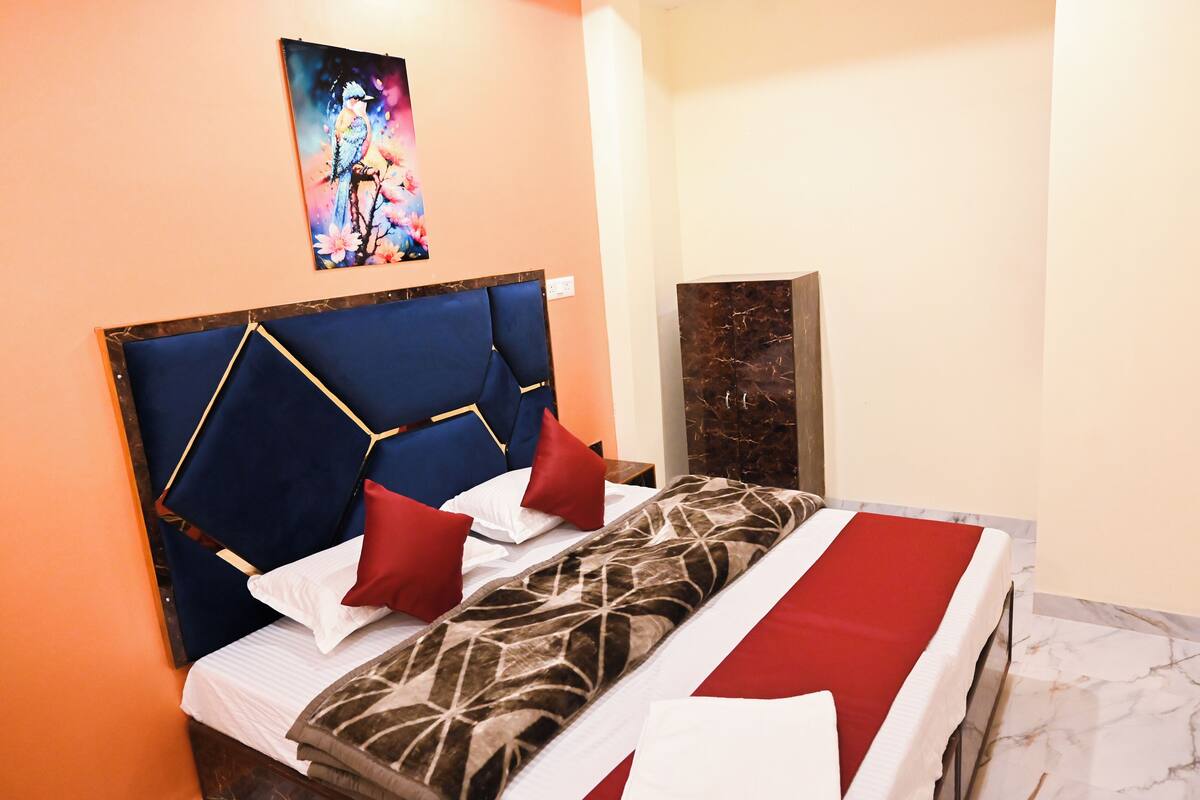 Una habitación de hotel con una cama, cabecera, un cuadro y suelo de mármol.