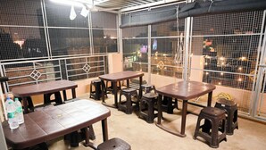 A dining area with tables and stools, surrounded by metal mesh walls. - Amaya Deluxe (Varanasi)