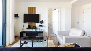 A modern living room with a sofa, coffee table, TV, and a console table with decorative items. - Luxury Apt Near Canary Wharf (Greater London)