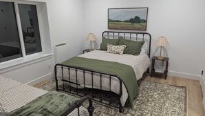 A bedroom with a bed, two bedside tables, a window, and a painting on the wall. - Newly constructed, charming, ski-on ski-off condo (Beaver)