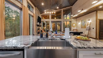 A kitchen with a marble countertop, stainless steel sink, and a fireplace.