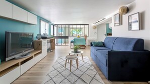 Una sala de estar moderna con televisor, sofá y comedor.