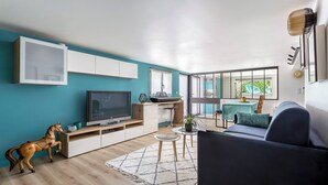 Una sala de estar moderna con televisor, sofá y comedor.