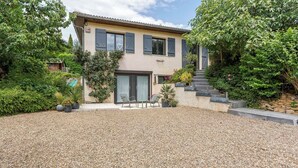 Una casa de dos pisos con camino de grava, una puerta principal y una escalera que sube al segundo piso.