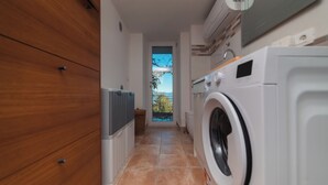 Een wasserette met een wasmachine, een droger en een houten kast.