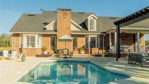 Une maison avec une piscine, un espace extérieur aménagé pour s’asseoir et une terrasse couverte.