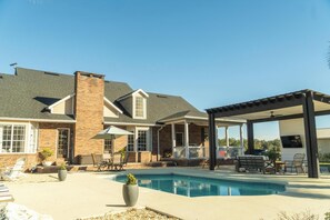A house with a swimming pool, patio furniture, and a covered outdoor area.