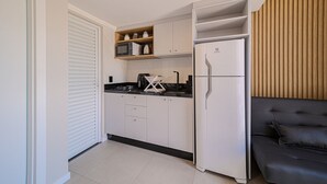 Een compacte keuken met witte kastjes, een zwart aanrecht en een ingebouwde magnetron.