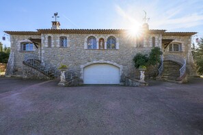 Un bâtiment en pierre avec une porte de garage blanche, un escalier et une statue.