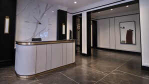 A reception area with a marble wall, a reception desk, and a tiled floor. - Premium Central Apartment • Eminescu Residence (Chișinău)