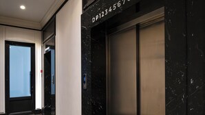 A modern elevator with a digital display, a marble wall, and a door with a frosted glass panel. - Premium Central Apartment • Eminescu Residence (Chișinău)