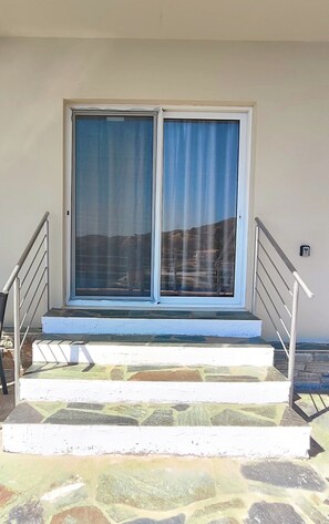 A set of outdoor stairs leading to a sliding glass door with a metal railing on either side.