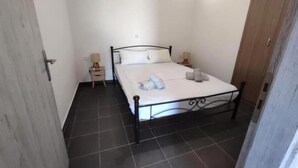 Une petite chambre propre, avec un lit, deux tables de chevet et une fenêtre.