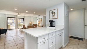 A spacious kitchen with a large island, white cabinetry, and a view to the dining area. - Upscale Unit with 2 King Beds-One Level-Pool Front- Steps to Sand Beach & Pier! (Cocoa Beach)
