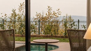 A poolside area with wicker chairs and a round table, overlooking a pool and vegetation. - Voger Sapanca Lake View (Sapanca)