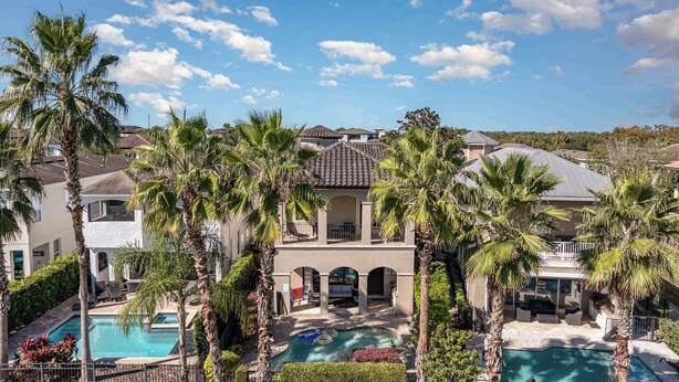 A large house with multiple pools, surrounded by palm trees and a clear blue sky. - Hollywood Glam Villa w/ AGT Stage Arcade Pool Spa! (Kissimmee)